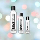 Three bottles of "Fuck Water Premium Silicone Lubricant" stand against a blurred background with colorful bokeh lights. Promising endless slippery fun, the bottles vary in size, with each label proudly displaying the product name for long-lasting performance.